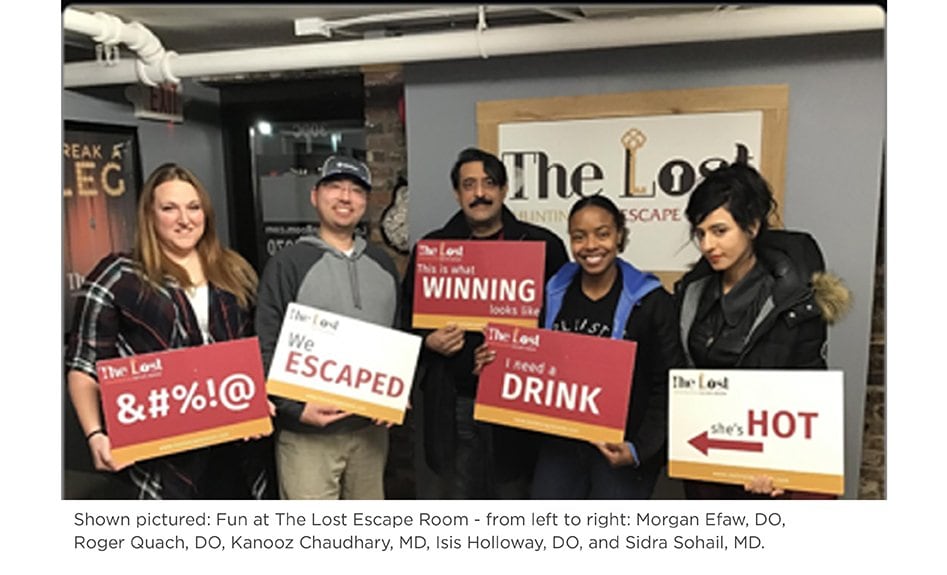 Several family medicine residents pose with signs at the Lost Escape Room.