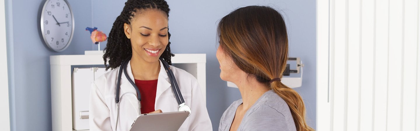 Physician holding tablet talking to patient